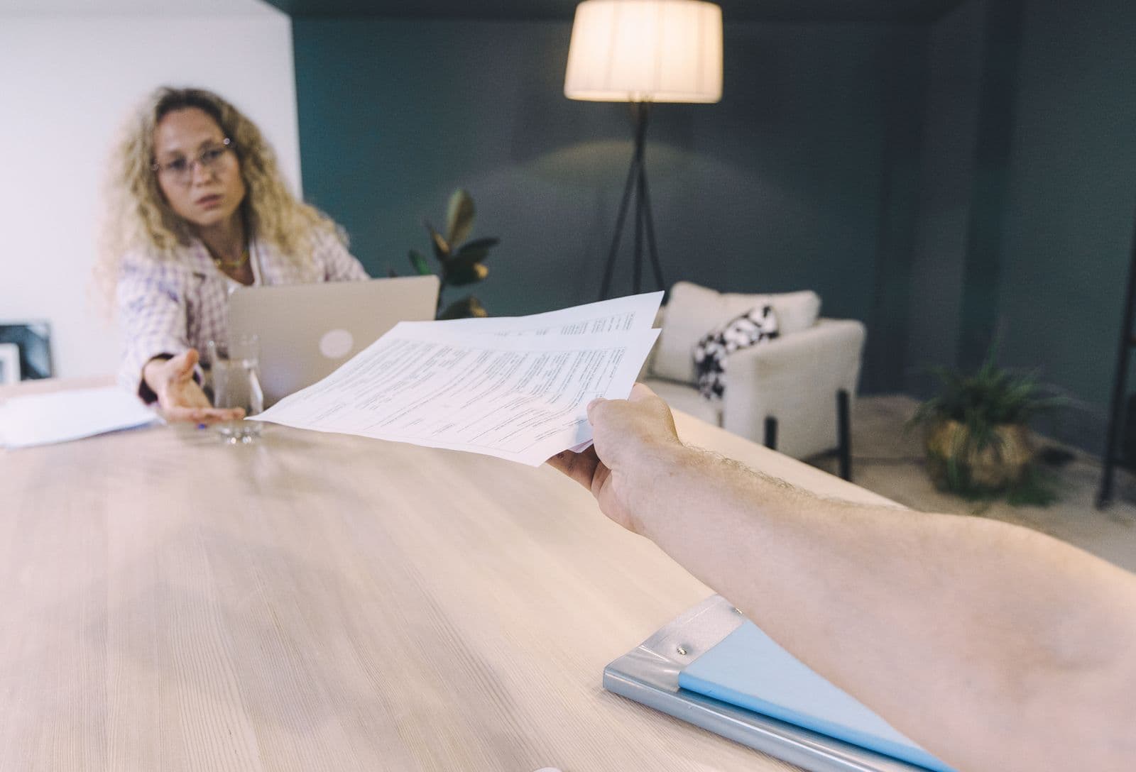 Une femme remet des documents par-dessus un bureau, dans un espace moderne.