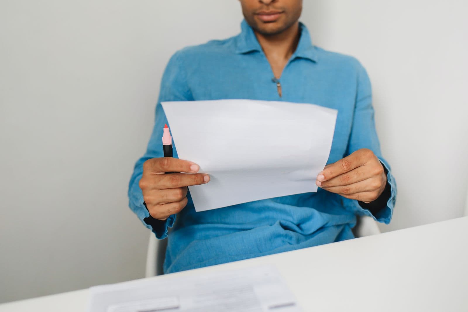 Un homme examine une feuille, un stylo à la main.